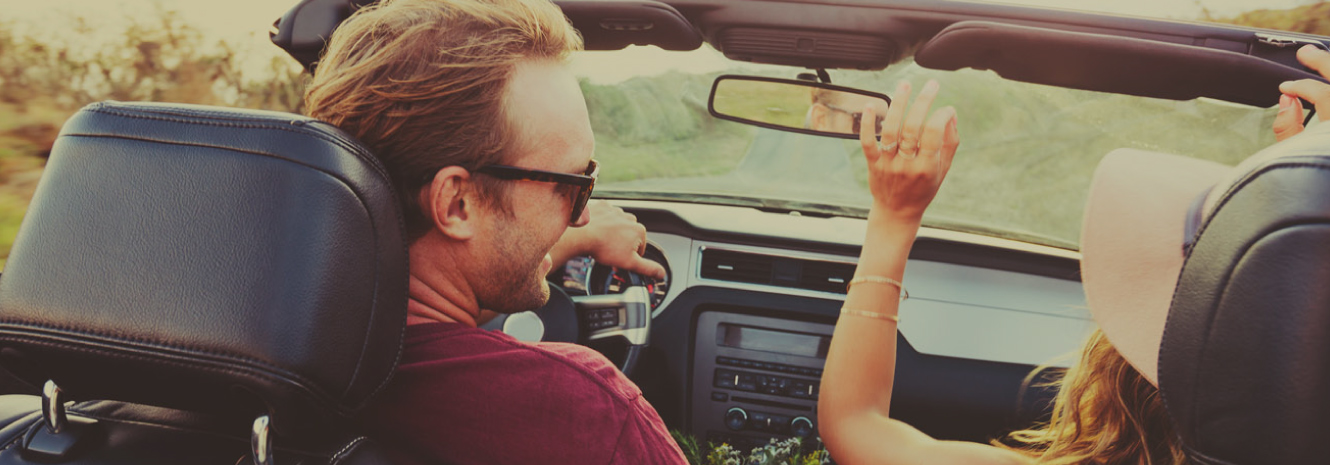 A couple riding in their new convertible.