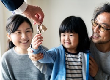 Young asian family buying a home, hands being given to girl