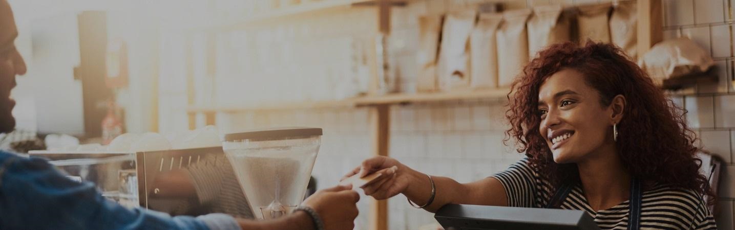 Female barista handing credit card back to customer