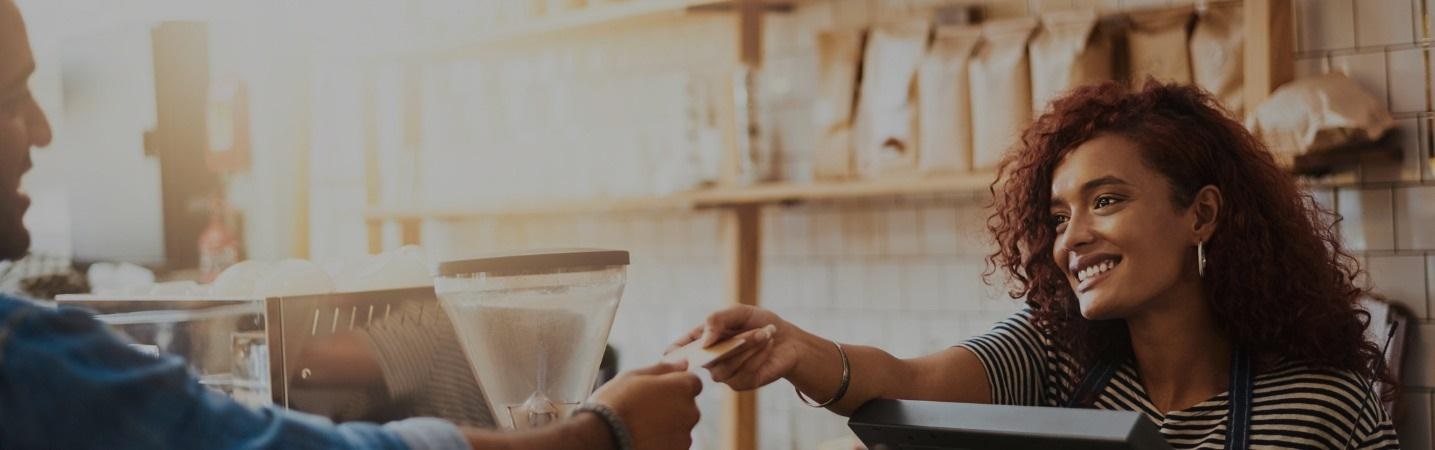 Female barista handing credit card back to customer