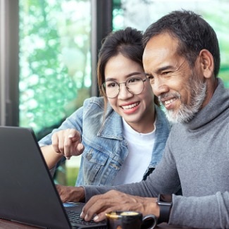 Mature father working on laptop with adult daughter
