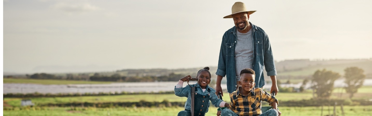 African American father pushing children in a wheelbarrow