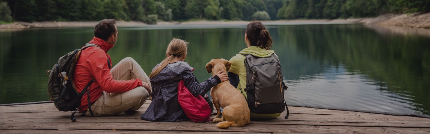 Family and dog sitting on pier overlooking a lake