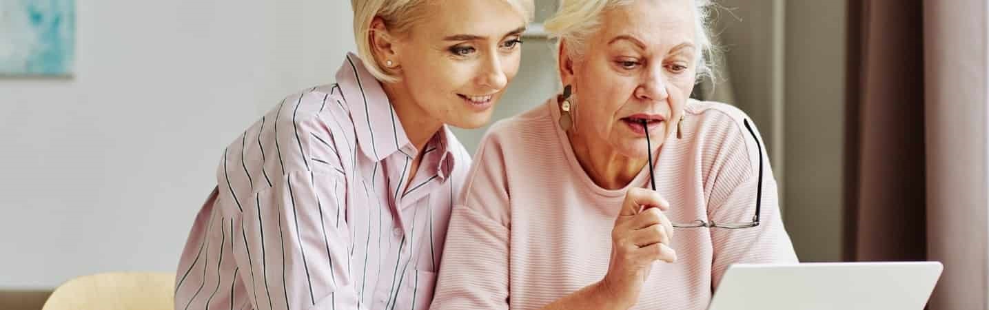 Daughter showing mother how to use laptop