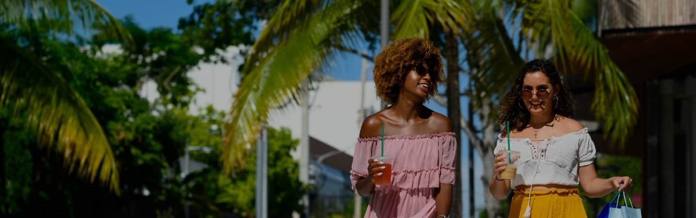 Two females friends enjoying a cold drink while walking down the street