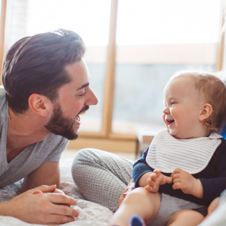 Dad smiling at laughing baby.