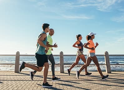 Group of friends jogging next to the ocean