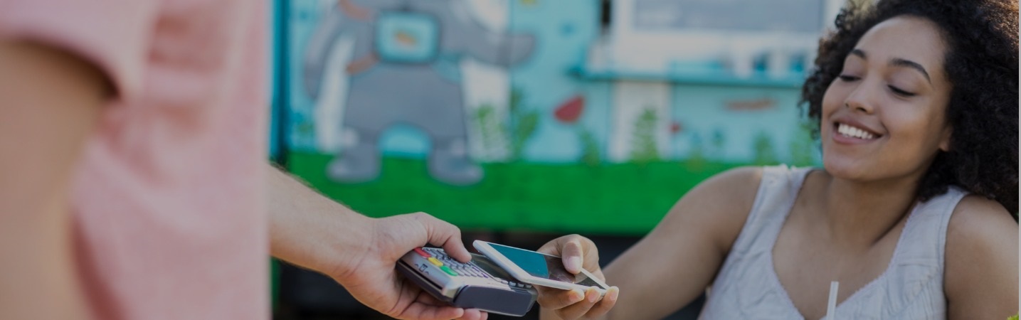 Smiling young woman using contactless payment with smart phone