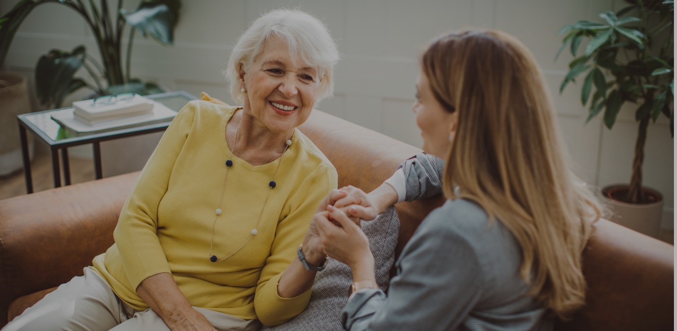 Happy senior mom chatting with her daughter on the couch