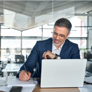 Happy business man writing at desk