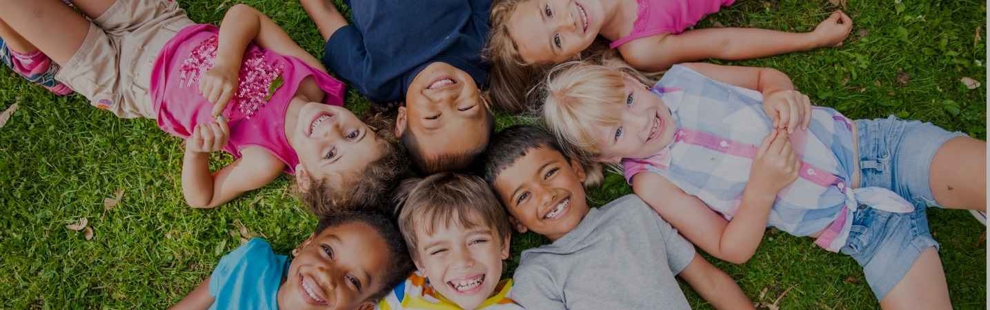 Group of children lying in a circle on grass in the summer