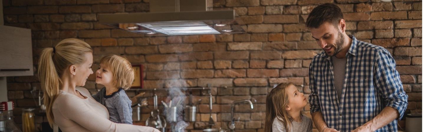 Young parents enjoying time preparing lunch in the kitchen with their kids