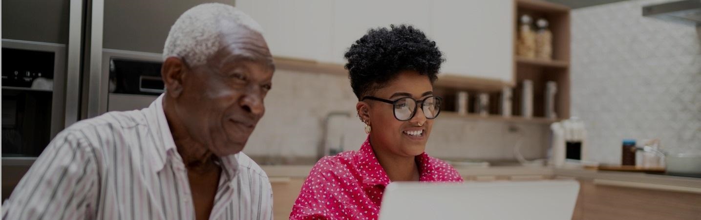 Granddaughter showing grandfather something on laptop