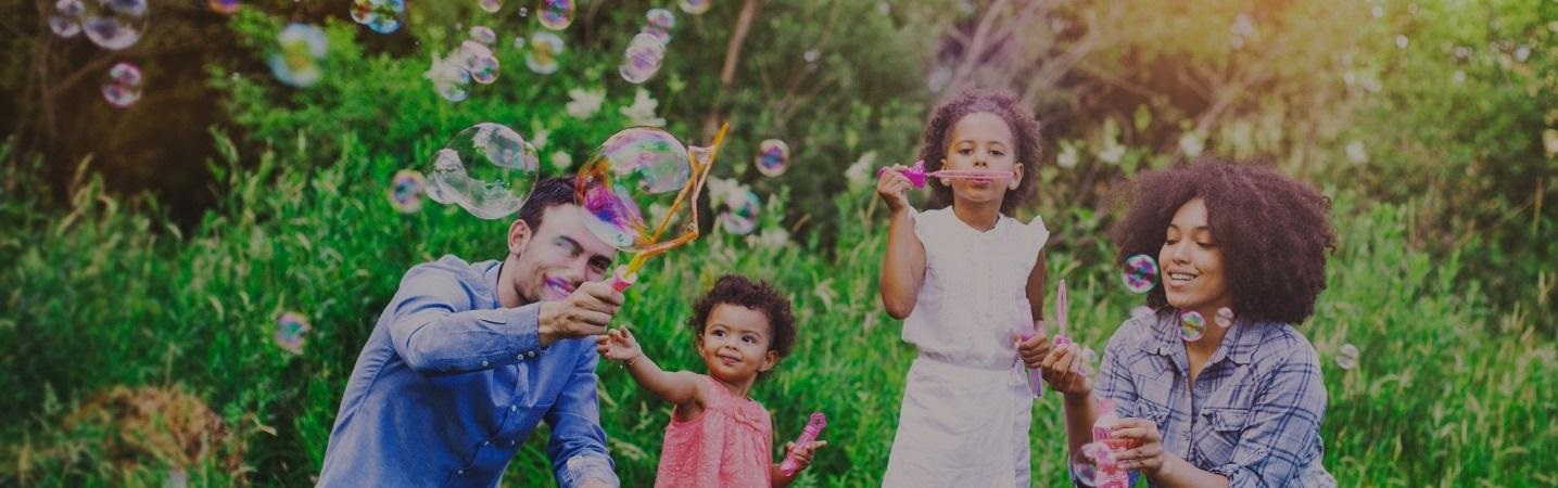 Happy family playing with soap bubbles in the park