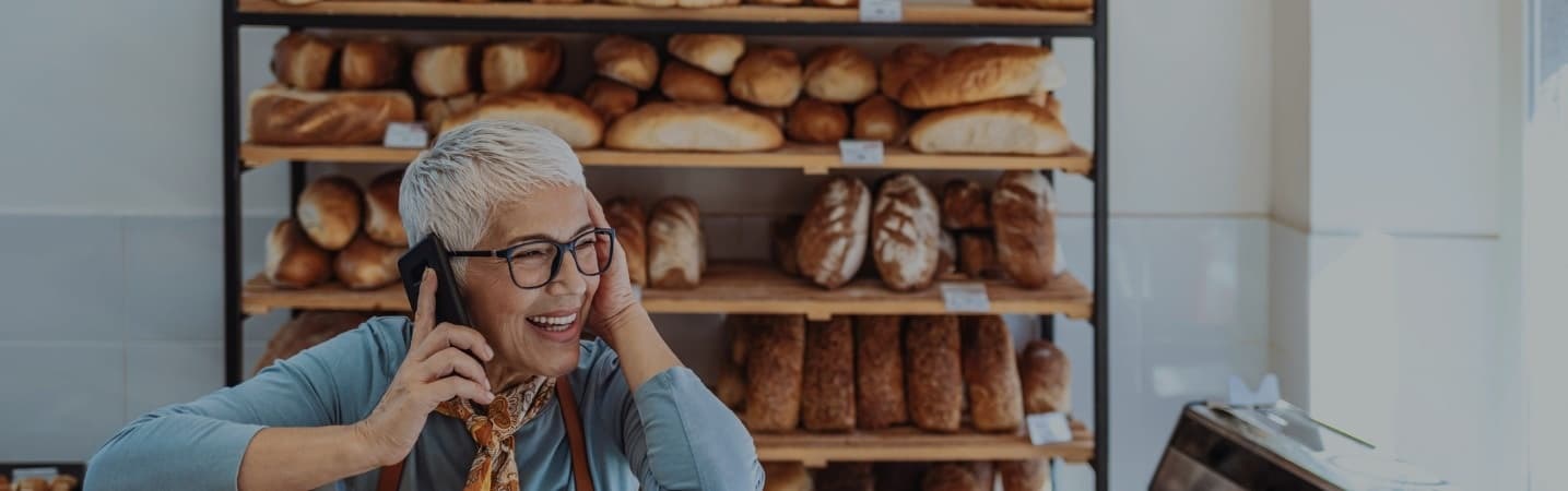 Smiling female bakery owner on phone