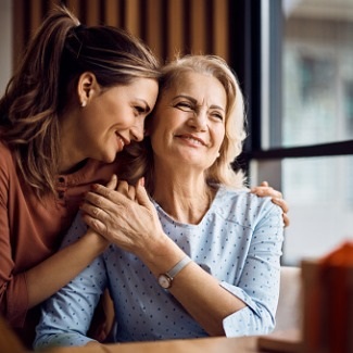 Mature mother being hugged by adult daughter