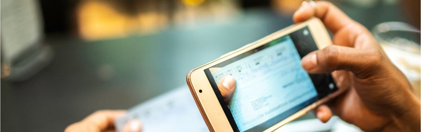 young woman depositing check by phone in a cafe