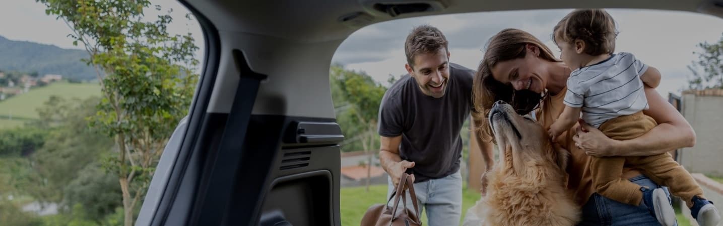 Young family loading bags into trunk of car.