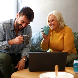Mature mother sharing a laugh and coffee where her adult son