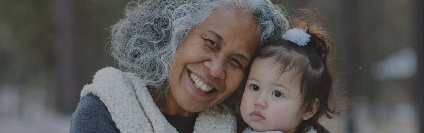 Ethnic grandmother holding granddaughter in the snow
