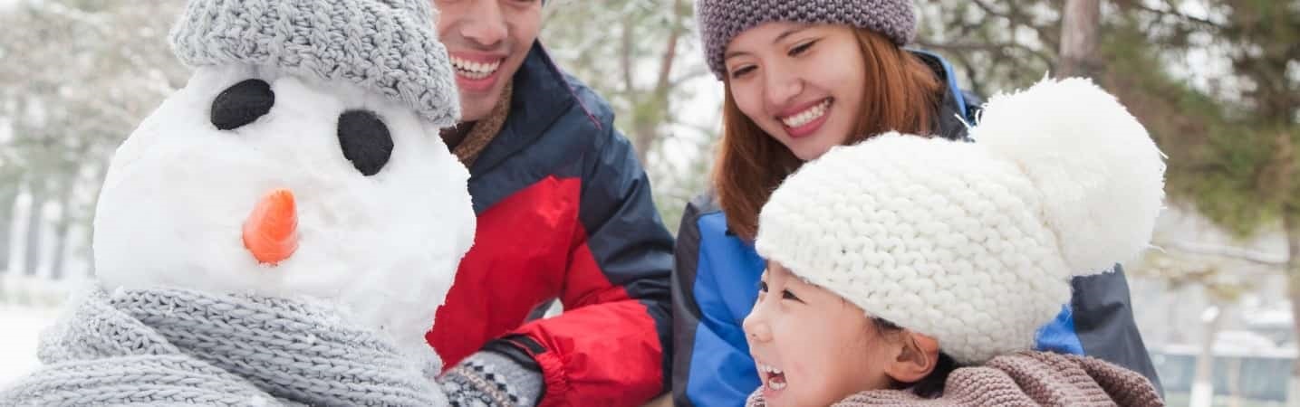 Asian family making a snowman