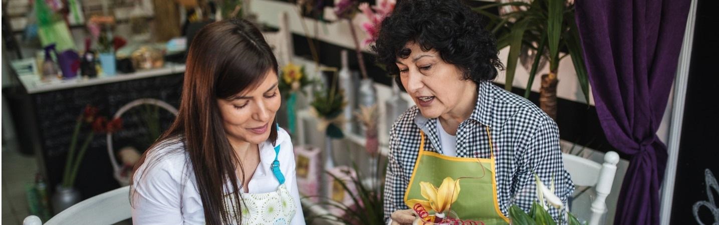 Lovely daughter taking notes about plans from her florist mother