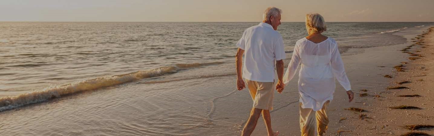 Happy senior couple taking a walking on the beach